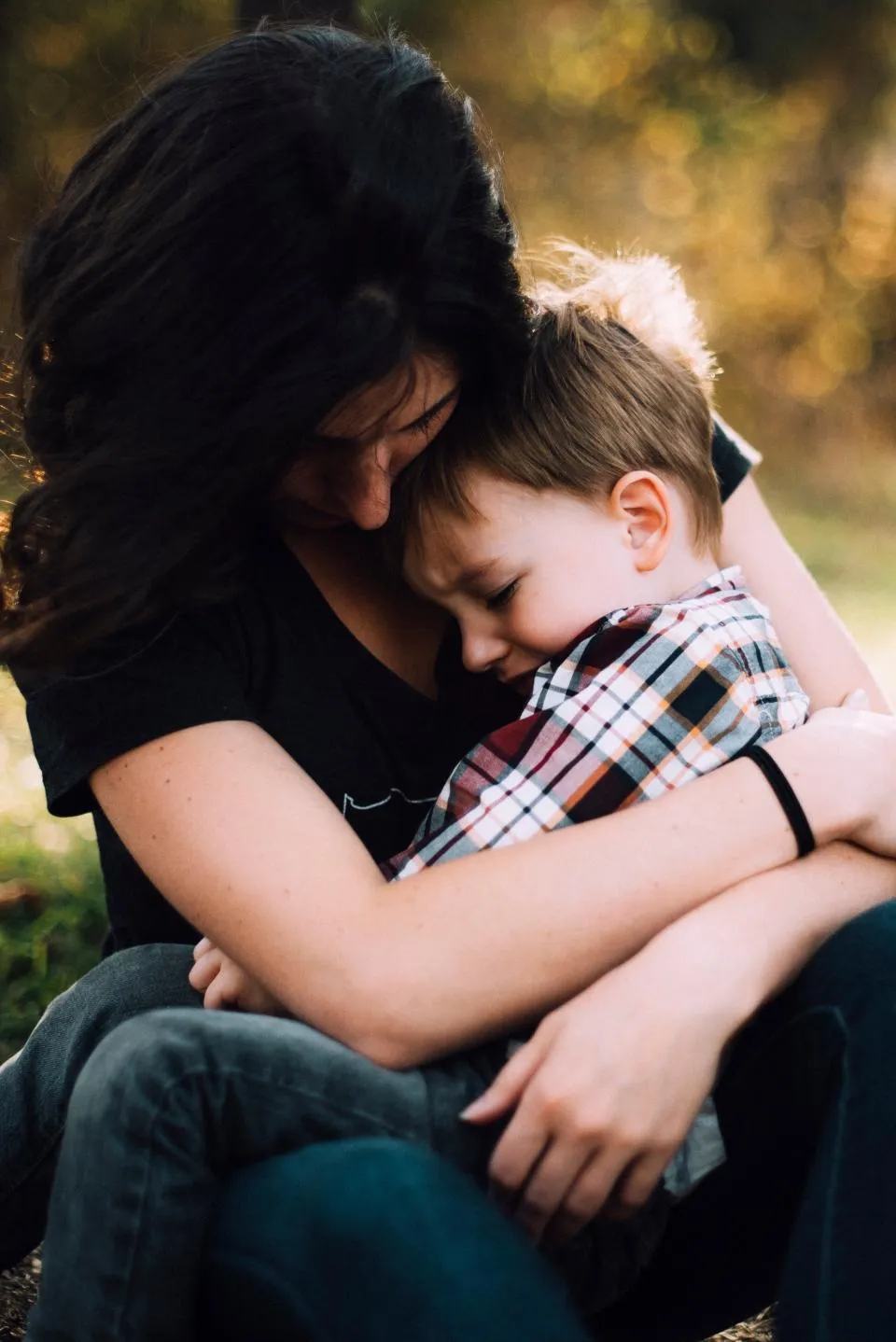 Mãe abraçando o filho pequeno, de olhos fechados